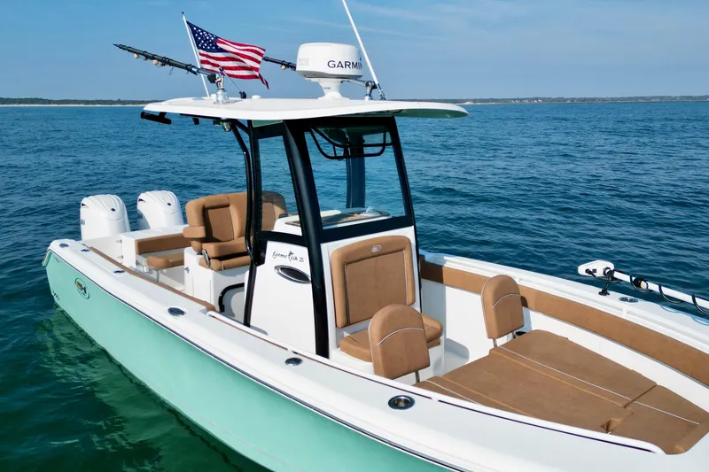 Slide: The Image of 2024 Sea Hunt Gamefish 25 boat on open water, featuring dual engines and American flag. - 10