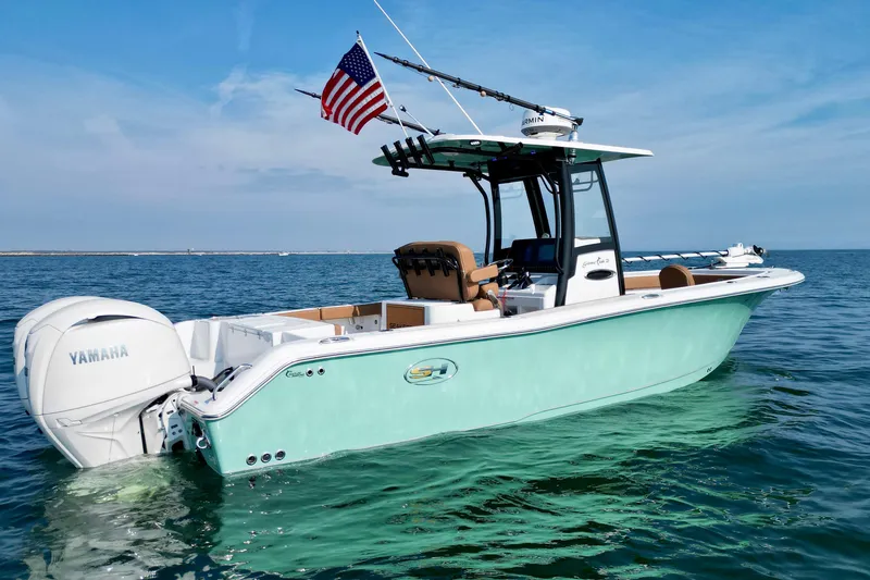 Slide: The Image of 2024 Sea Hunt Gamefish 25 boat on water with American flag and Yamaha engine. - 11
