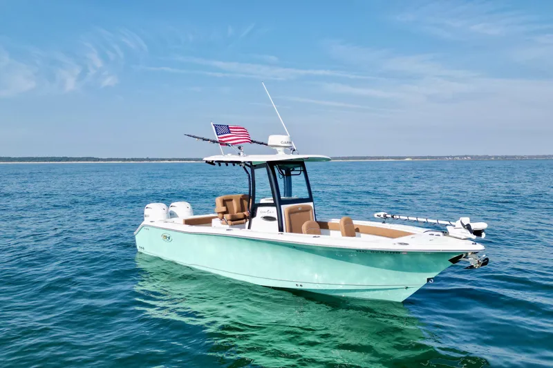 Slide: The Image of 2024 Sea Hunt Gamefish 25 boat on open water, featuring dual engines and American flag. - 12