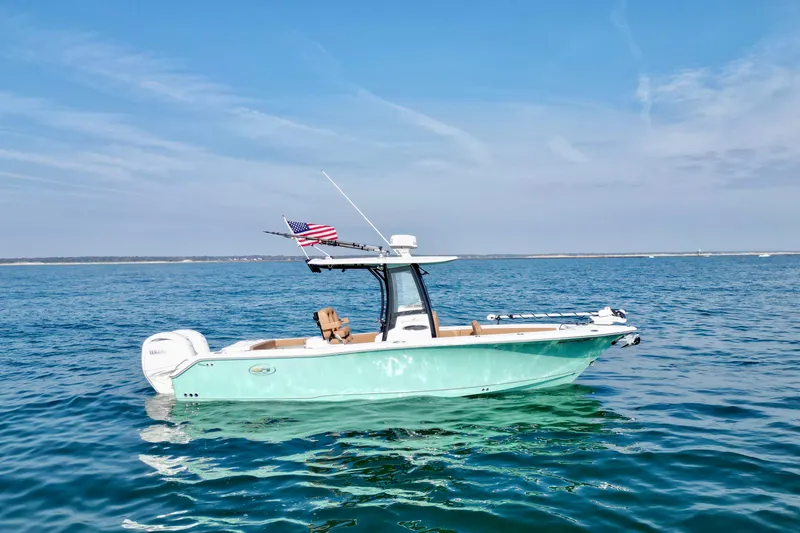 Slide: The Image of 2024 Sea Hunt Gamefish 25 boat on open water with American flag. - 2
