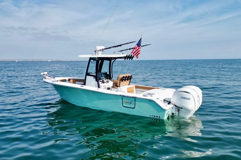 Slide: The Image of 2024 Sea Hunt Gamefish 25 boat on calm ocean waters with American flag. - 6
