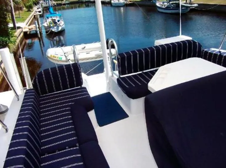 Slide: The Image of Mainship 430 Trawler 2000 with striped seating on deck, docked near other boats. - 3