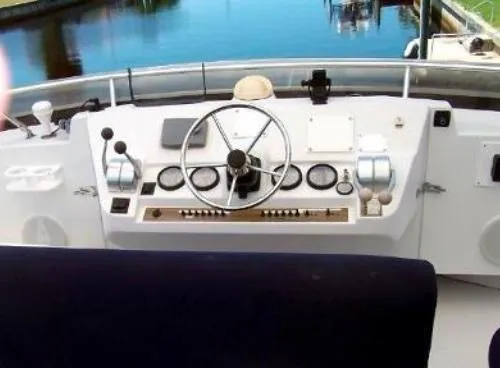 Slide: The Image of Mainship 430 Trawler 2000 helm with steering wheel and controls, docked by calm water. - 6