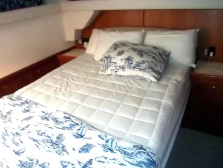 Slide: The Image of Mainship 430 Trawler 2000 bedroom with white bedding and floral pillows. - 7