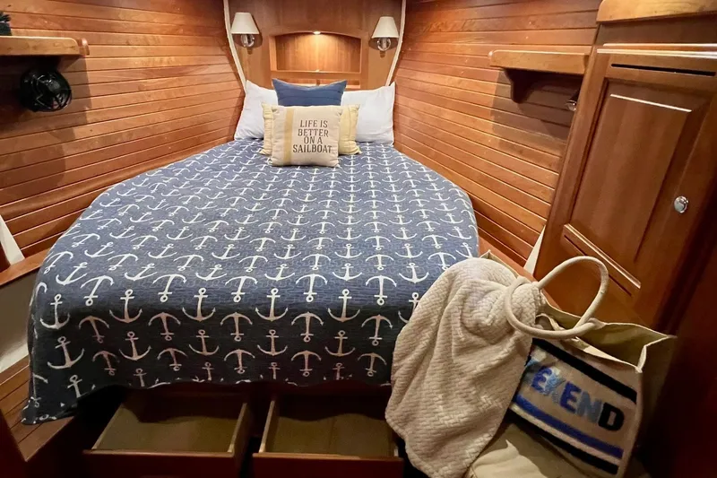 Slide: The Image of Cozy Tartan 4300 sailboat cabin with anchor-themed bedding, wooden interior, and nautical decor. - 14