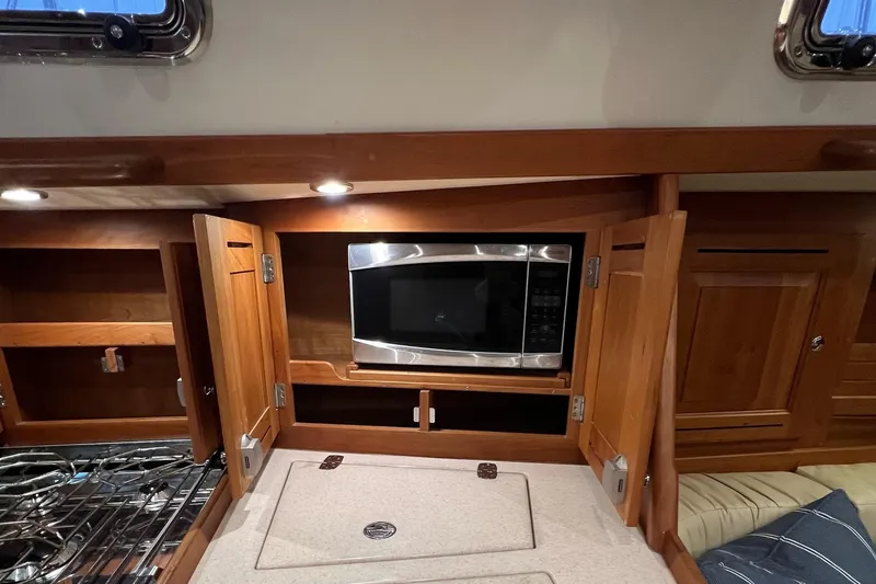 Slide: The Image of 2017 Tartan 4300 yacht kitchen with microwave, wooden cabinets, and stove. - 40