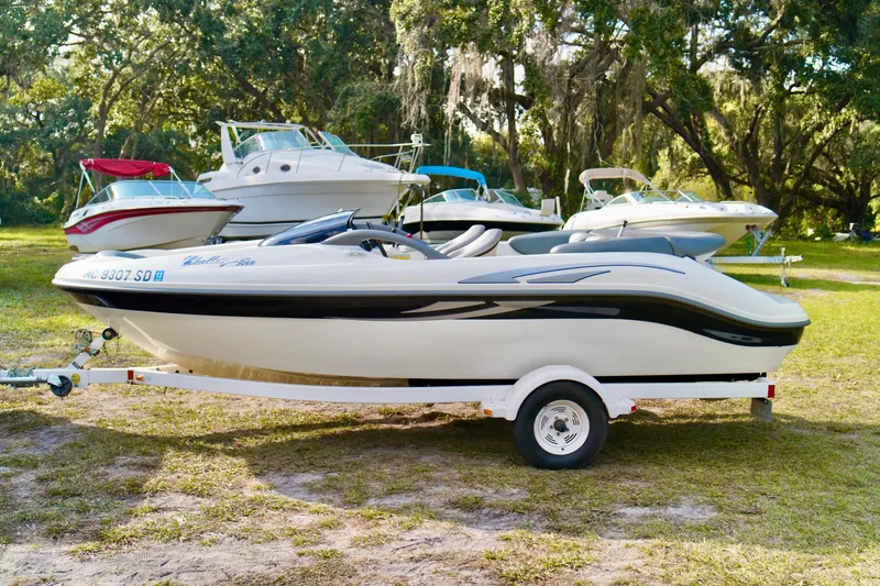 Slide: The Image of 2001 Bombardier 1800 Challenger boat on trailer, surrounded by other boats, in a grassy area. - 4