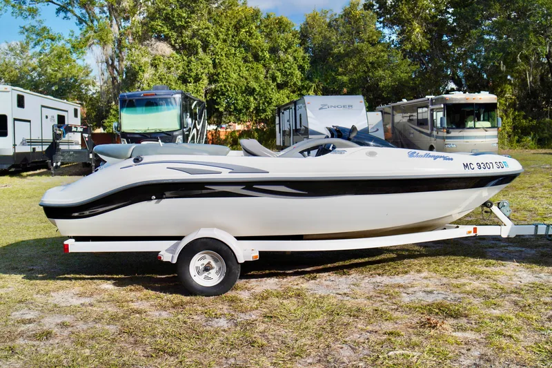 Slide: The Image of 2001 Bombardier 1800 Challenger boat on trailer, parked near RVs and trees. - 5