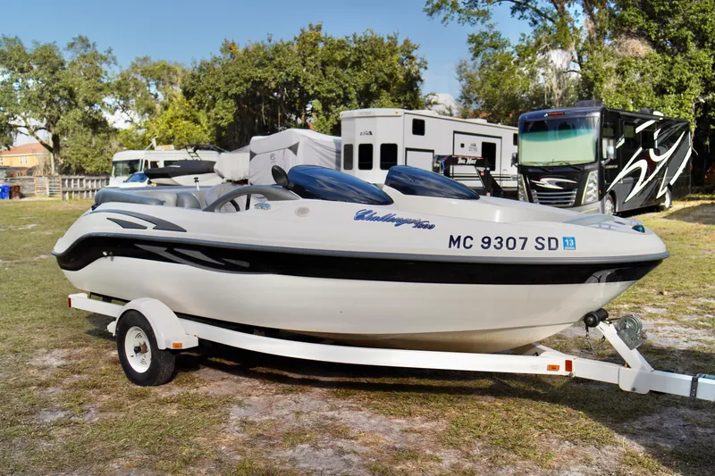 Slide: The Image of 2001 Bombardier 1800 Challenger boat on trailer, parked outdoors near RVs. - 6
