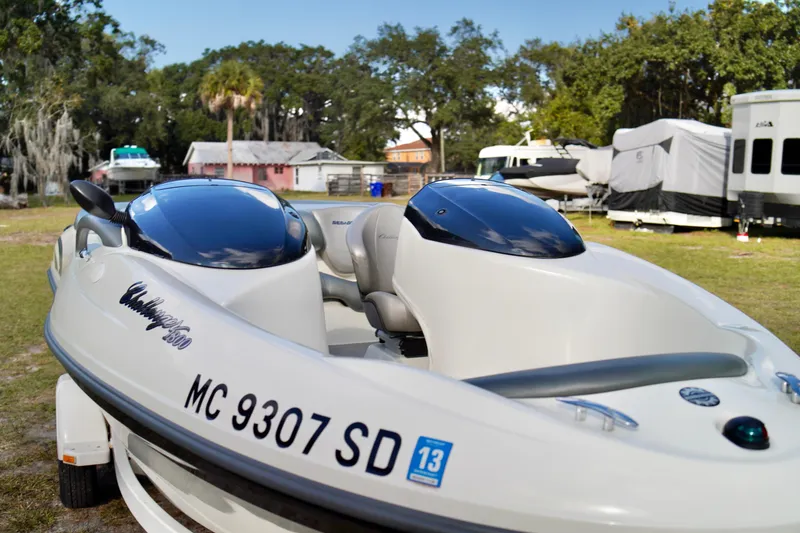 Slide: The Image of 2001 Bombardier 1800 Challenger boat parked outdoors, surrounded by trees and trailers. - 8