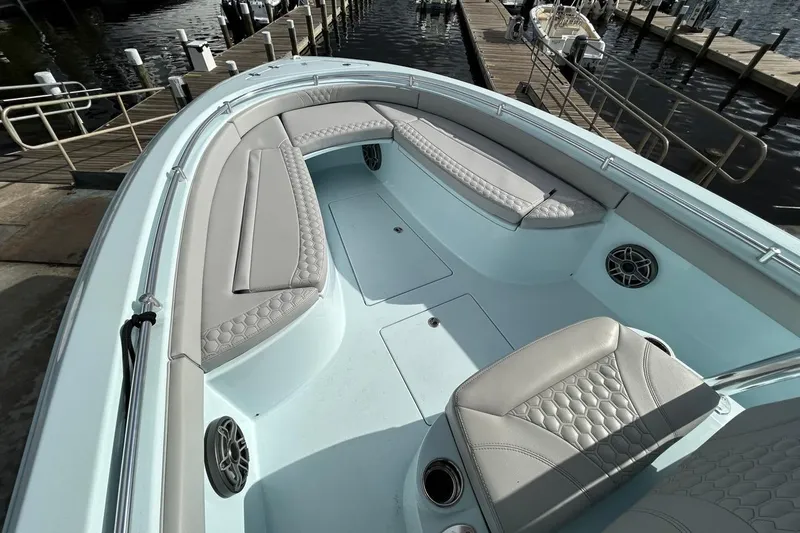 Slide: The Image of 2024 Contender 24 Sport boat interior with cushioned seating and speakers at a dock. - 10