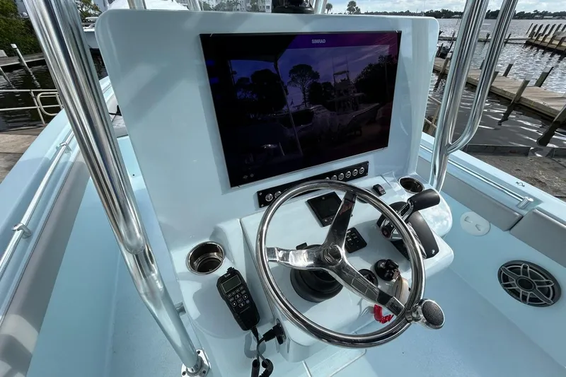 Slide: The Image of 2024 Contender 24 Sport boat dashboard with steering wheel and navigation display. - 16