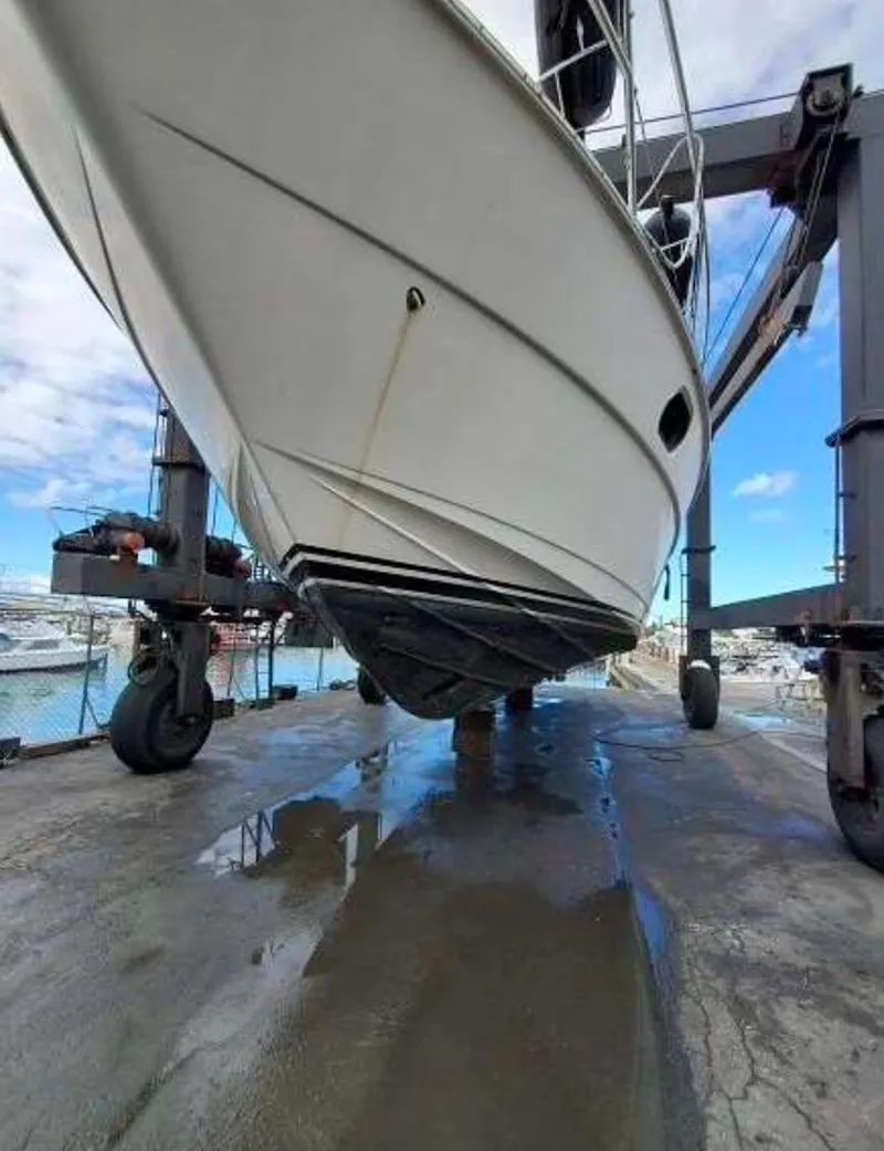 Slide: The Image of 1998 Viking Sports Cruiser on a lift at a marina, showcasing its hull design. - 16