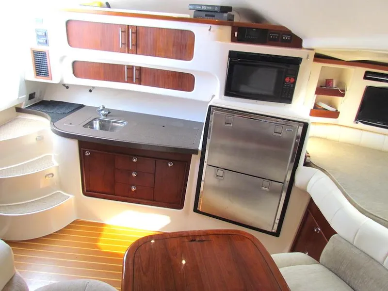 Slide: The Image of 2008 Grady-White Express 360 interior with kitchenette, wood cabinets, and stainless steel appliances. - 21