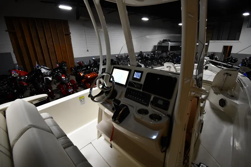 Slide: The Image of 2022 Boston Whaler 250 Dauntless boat interior with control panel in a dimly lit showroom. - 17