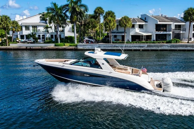 The Image of 2019 Sea Ray SLX 400 Outboard cruising on a sunny waterfront with palm trees. - 0
