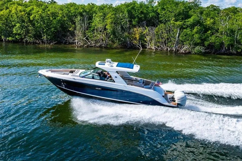 Slide: The Image of 2019 Sea Ray SLX 400 Outboard cruising on a scenic waterway with lush greenery. - 13