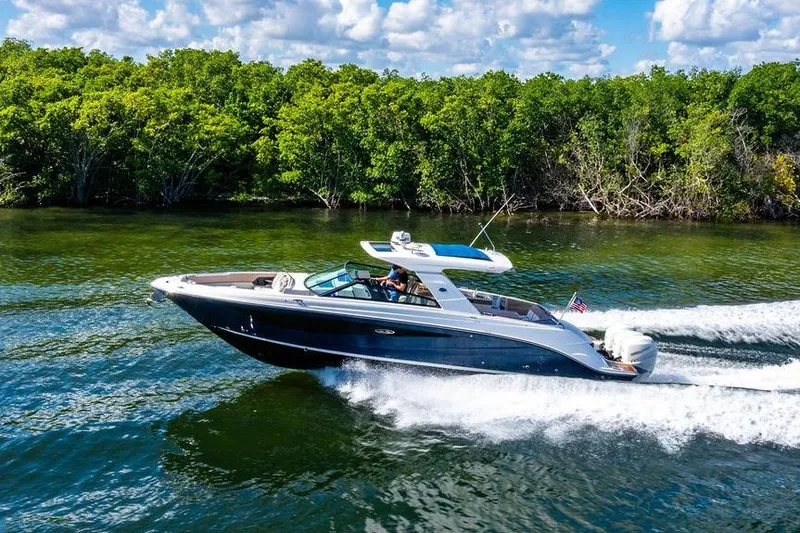 Slide: The Image of 2019 Sea Ray SLX 400 Outboard cruising on a scenic waterway with lush greenery. - 14