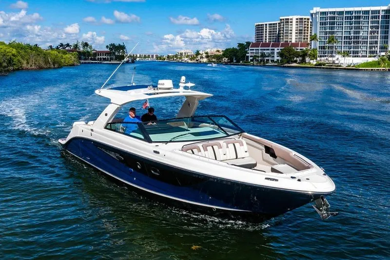 Slide: The Image of 2019 Sea Ray SLX 400 Outboard cruising on a scenic waterway with modern buildings. - 17