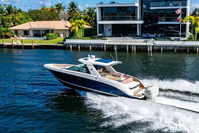 Slide: The Image of 2019 Sea Ray SLX 400 Outboard cruising near luxury waterfront homes. - 2