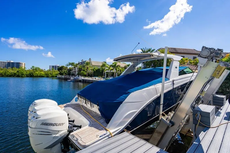 Slide: The Image of 2019 Sea Ray SLX 400 Outboard docked, covered, with Mercury engines, under clear blue sky. - 20