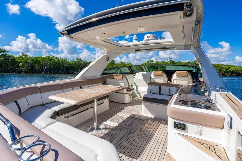 Slide: The Image of 2019 Sea Ray SLX 400 Outboard luxury boat interior with seating and table, under blue sky. - 28