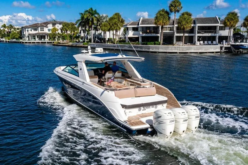 Slide: The Image of 2019 Sea Ray SLX 400 Outboard cruising on a sunny waterfront with palm trees. - 3
