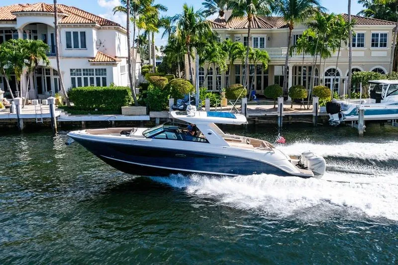 Slide: The Image of 2019 Sea Ray SLX 400 Outboard cruising near luxury waterfront homes. - 5
