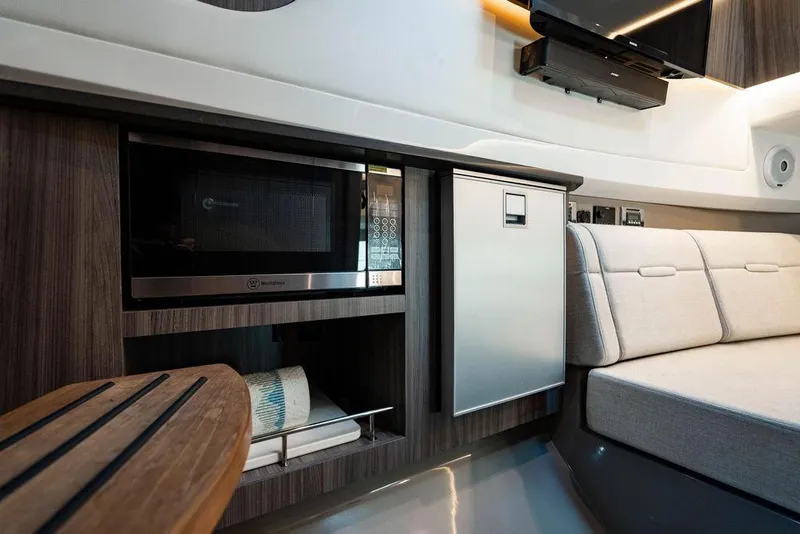 Slide: The Image of 2019 Sea Ray SLX 400 Outboard interior with microwave, fridge, and seating area. - 56