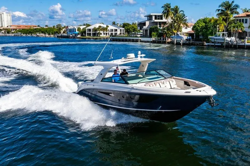 Slide: The Image of 2019 Sea Ray SLX 400 Outboard cruising on a sunny waterfront with luxury homes. - 7