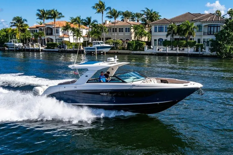 Slide: The Image of 2019 Sea Ray SLX 400 Outboard cruising on a scenic waterway with luxury homes. - 9