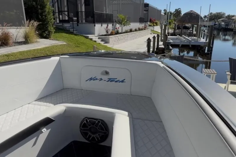 Slide: The Image of 2022 Nor-Tech 390 Sport boat interior with white seating and speaker, dockside view. - 22