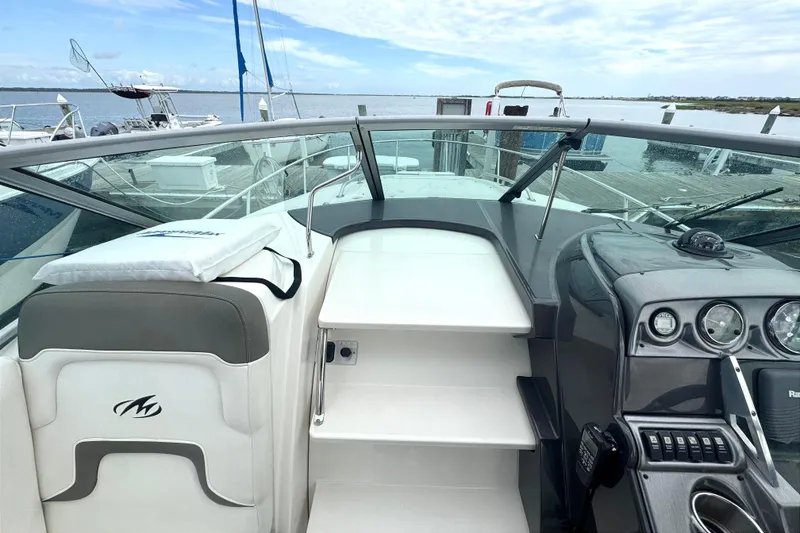 Slide: The Image of 2013 Monterey 260 SCR boat interior with dashboard and seating, docked by the water. - 8
