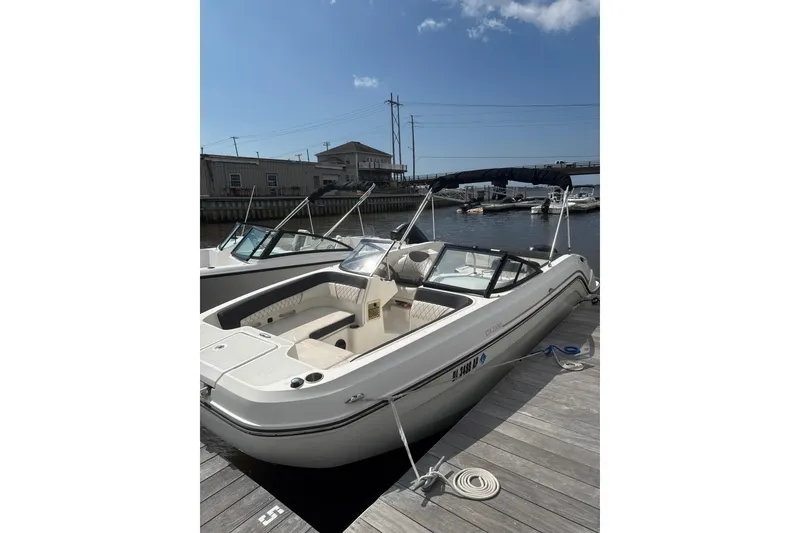 The Image of 2023 Bayliner DX 2200 boat docked at a marina under a clear blue sky. - 0