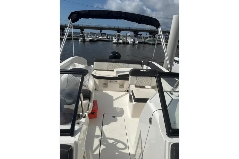 Slide: The Image of 2023 Bayliner DX 2200 boat interior with seating, docked at marina. - 2