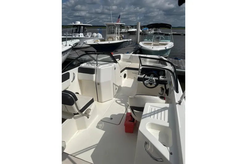 Slide: The Image of 2023 Bayliner DX 2200 boat interior at a marina, featuring seating and steering console. - 3