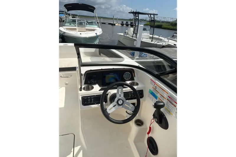 Slide: The Image of 2023 Bayliner DX 2200 boat dashboard with steering wheel and controls at marina. - 4