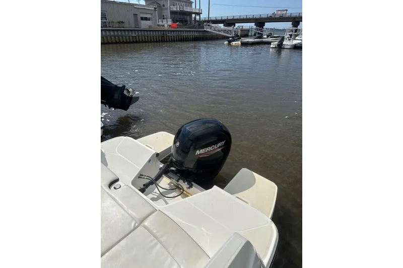 Slide: The Image of 2023 Bayliner DX 2200 boat with Mercury outboard motor docked by a marina. - 7