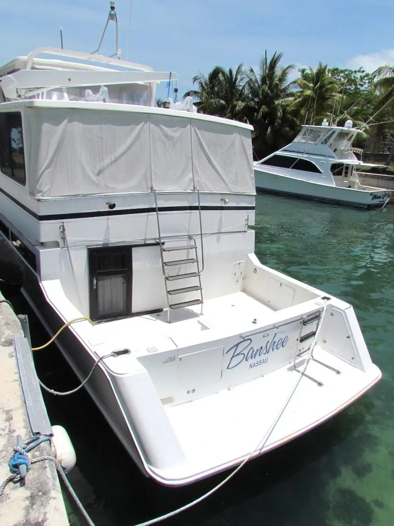 Slide: The Image of 1997 Hyatt 55 yacht docked, featuring a spacious deck and tropical backdrop. - 3