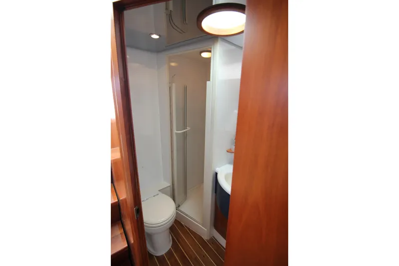 Slide: The Image of 2008 Bertram 360 yacht bathroom with shower, toilet, and wooden accents. - 40