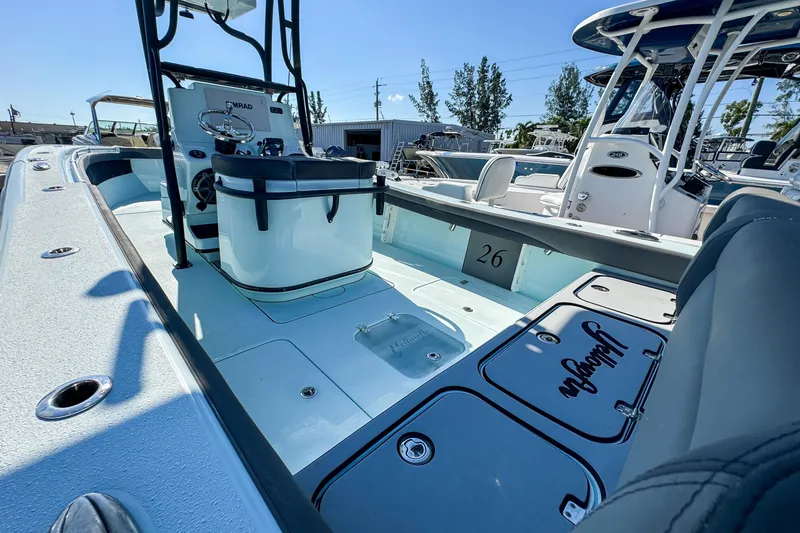 Slide: The Image of 2019 Yellowfin 26 Hybrid boat interior with seating and console, docked outdoors. - 13