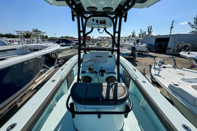 Slide: The Image of 2019 Yellowfin 26 Hybrid boat interior with steering console, docked among other boats. - 16
