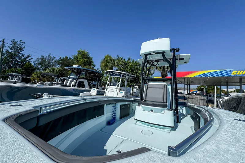 Slide: The Image of 2019 Yellowfin 26 Hybrid boat with elevated helm, parked outdoors under clear blue sky. - 2