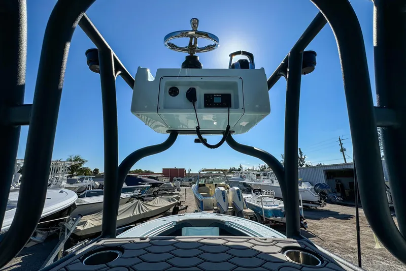 Slide: The Image of 2019 Yellowfin 26 Hybrid boat console with steering wheel, docked under clear blue sky. - 21