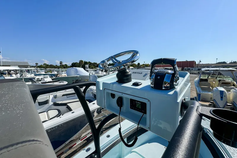 Slide: The Image of 2019 Yellowfin 26 Hybrid boat console with steering wheel and controls, docked under clear blue sky. - 23