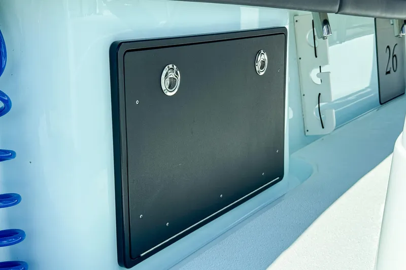 Slide: The Image of 2019 Yellowfin 26 Hybrid boat storage compartment with sleek black panel and chrome handles. - 32