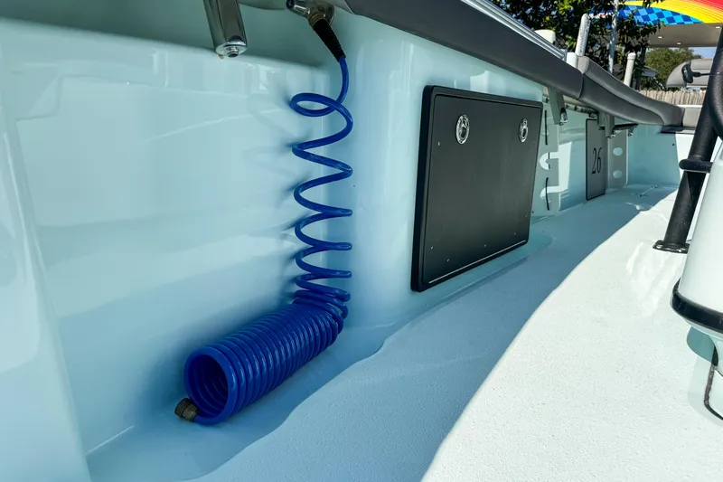 Slide: The Image of 2019 Yellowfin 26 Hybrid boat interior with blue coiled hose and storage compartment. - 33
