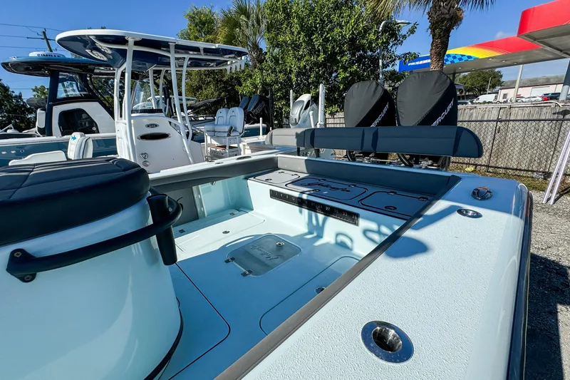 Slide: The Image of 2019 Yellowfin 26 Hybrid boat with spacious deck and seating, parked outdoors. - 9