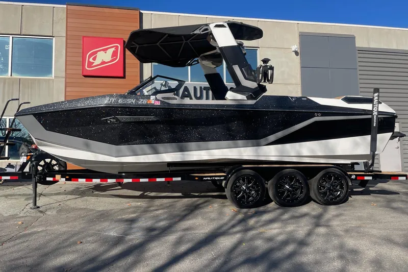 The Image of 2025 Nautique Super Air Nautique G25 Paragon boat on trailer outside dealership. - 1