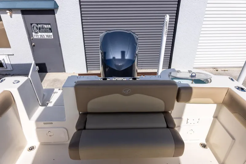 Slide: The Image of 2018 Sailfish 241 CC boat interior with seating and motor, docked near marine service. - 18